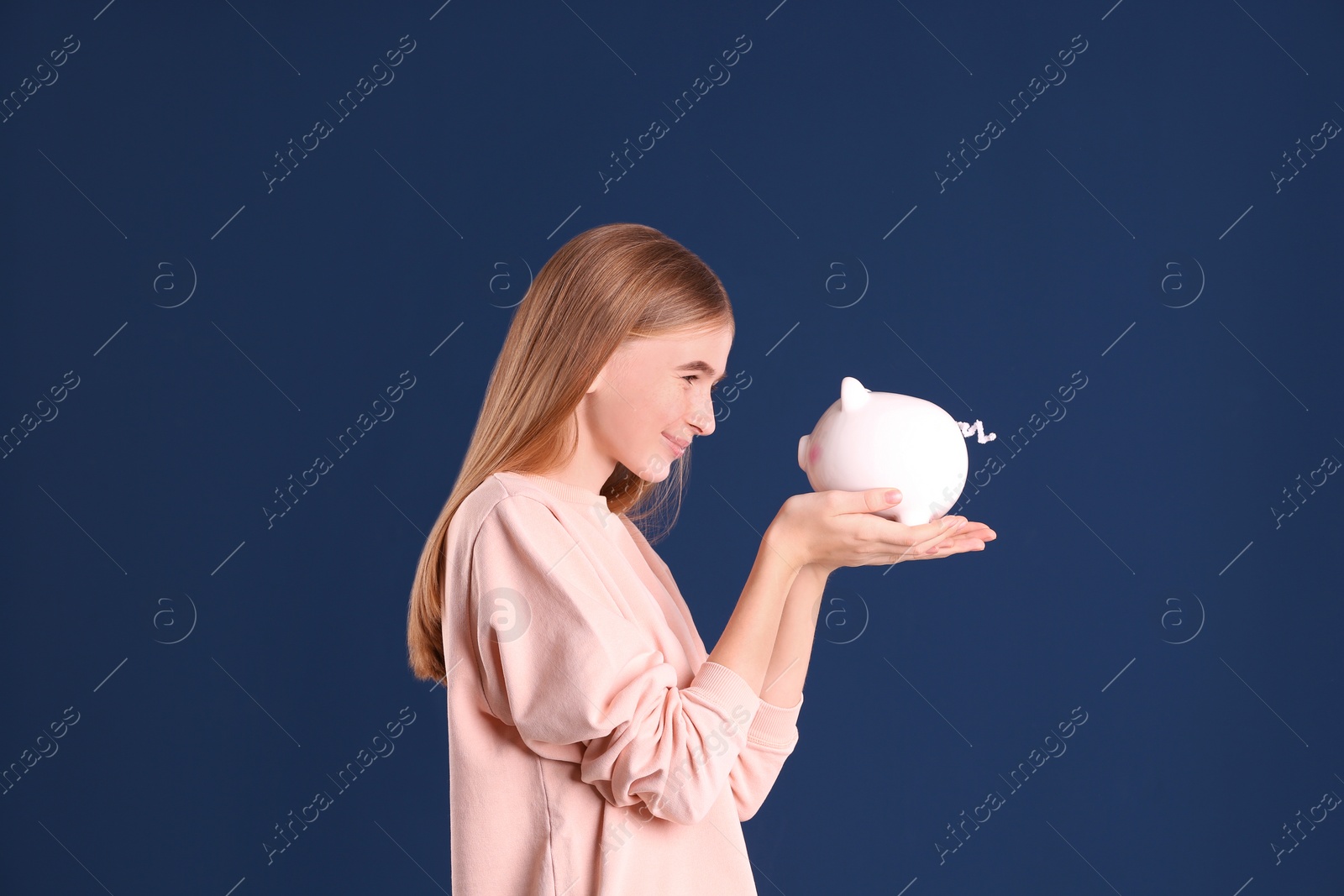 Photo of Teen girl with piggy bank on color background