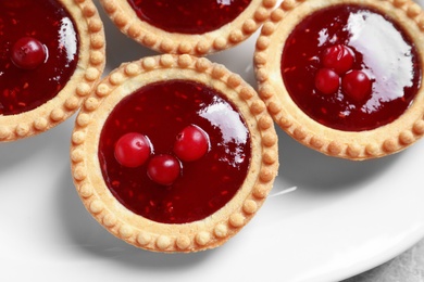 Tasty tartlets with jam on plate, closeup