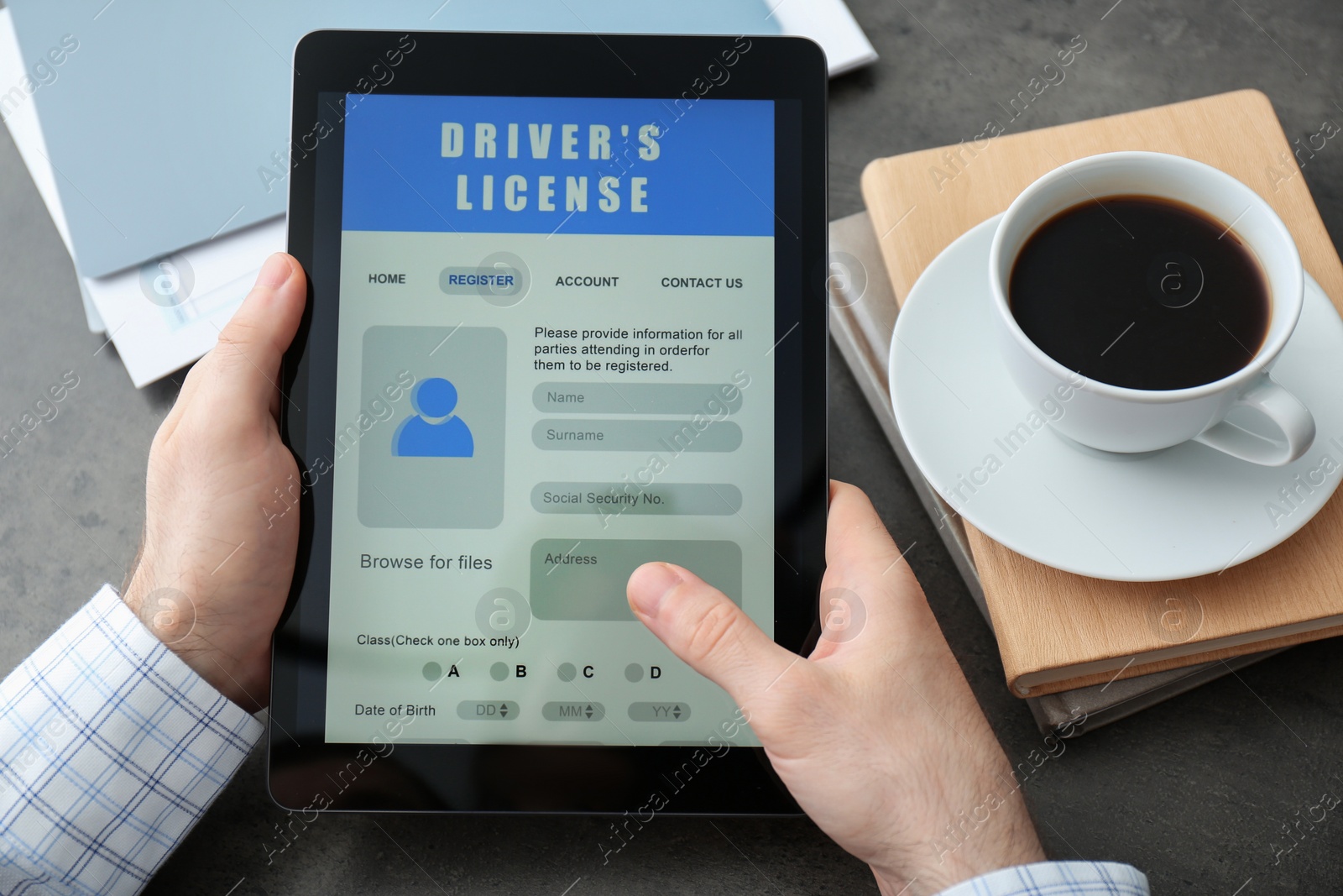 Photo of Man holding tablet with driver's license application form at grey table, closeup