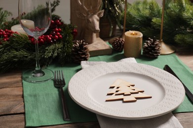 Festive place setting with beautiful dishware, cutlery and decor for Christmas dinner on wooden table