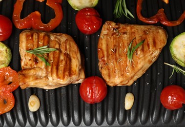 Photo of Tasty meat, spices and vegetables on electric grill, flat lay