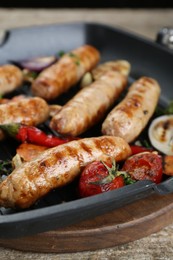 Photo of Tasty fresh grilled sausages with vegetables on wooden table, closeup