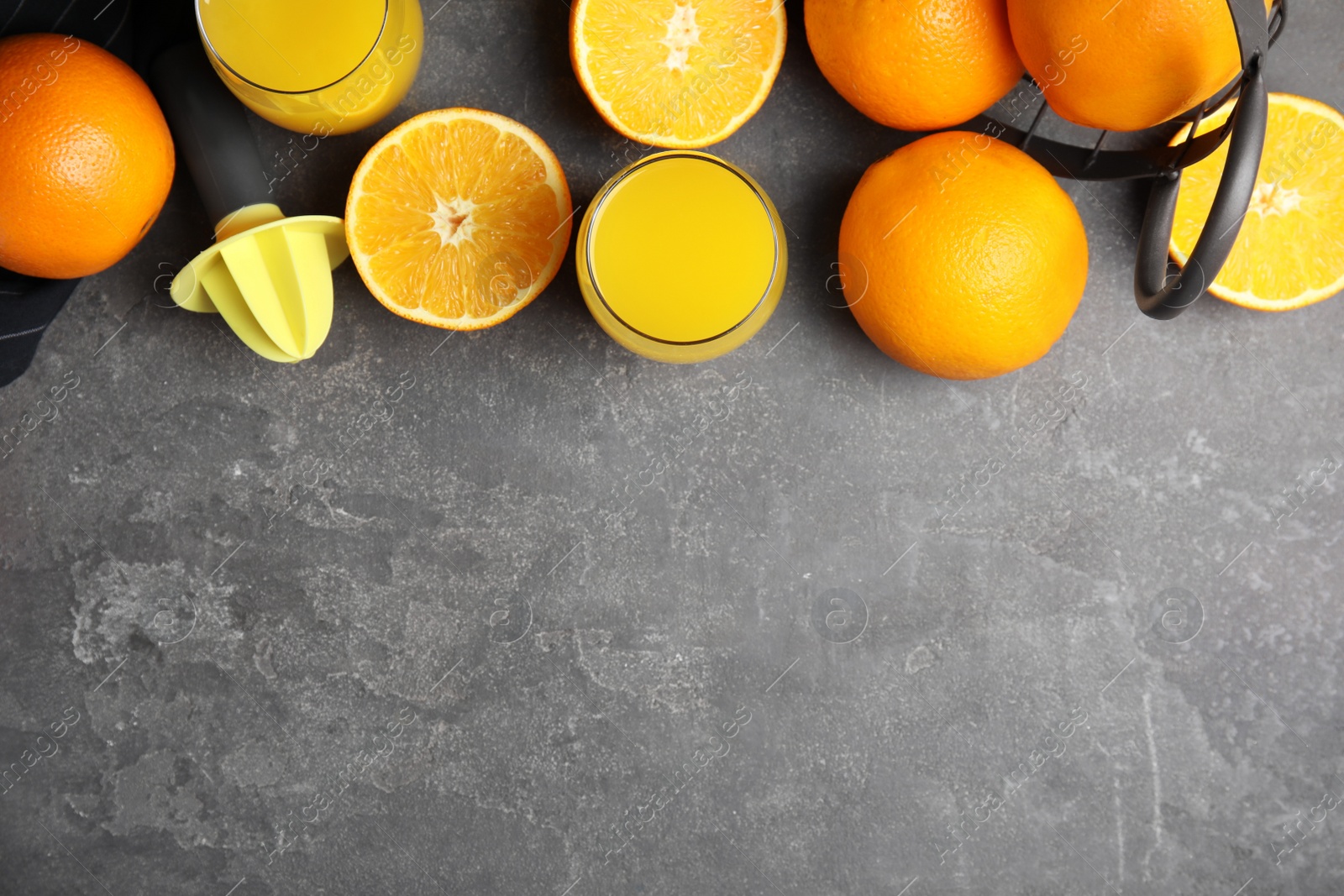 Photo of Fresh ripe oranges, reamer and juice on grey table, flat lay. Space for text