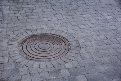 Photo of Metal sewer hatch on street tiles outdoors, space for text