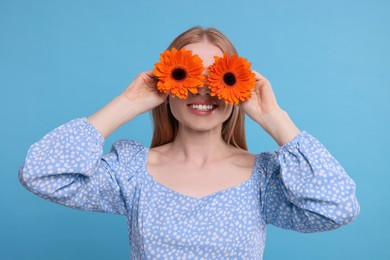Photo of Woman covering her eyes with spring flowers on light blue background