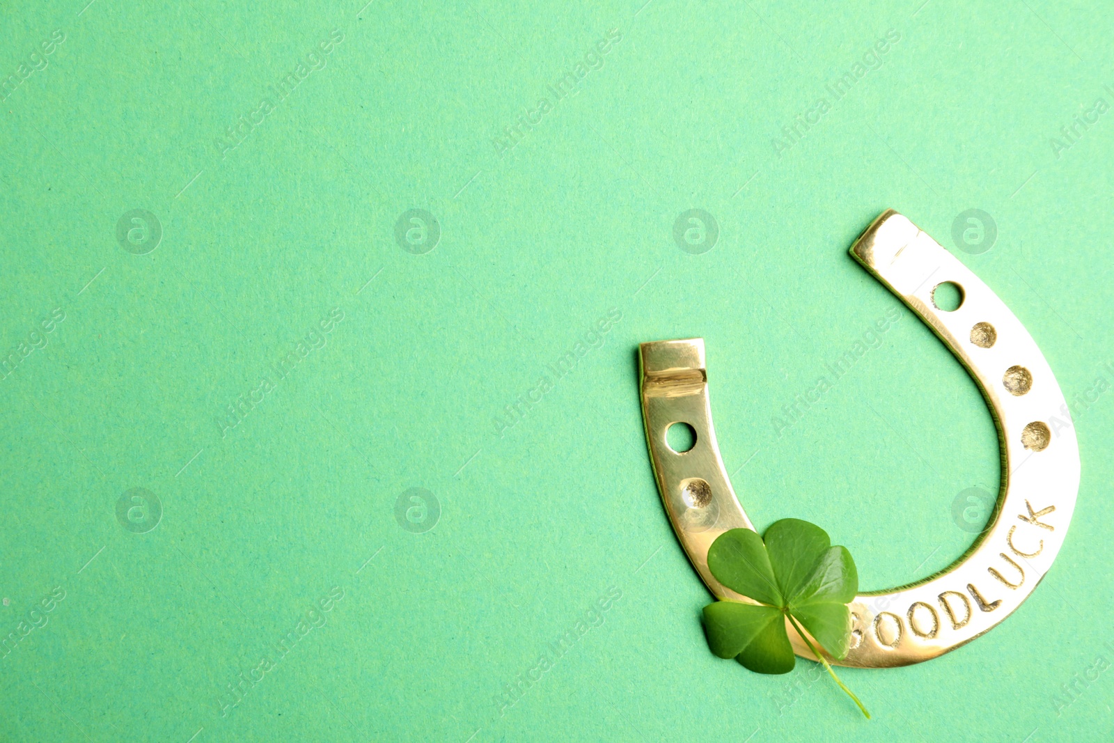 Photo of Clover leaf and horseshoe on green background, flat lay with space for text. St. Patrick's Day celebration