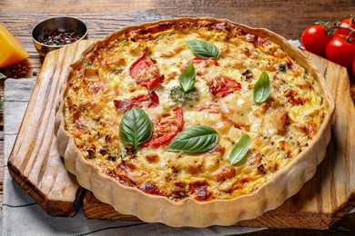 Photo of Tasty quiche with tomatoes, basil and cheese on wooden table, closeup