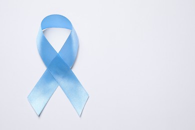 Photo of International Psoriasis Day. Light blue ribbon as symbol of support on white background, top view. Space for text