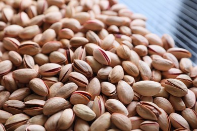 Many tasty pistachios on table, closeup view