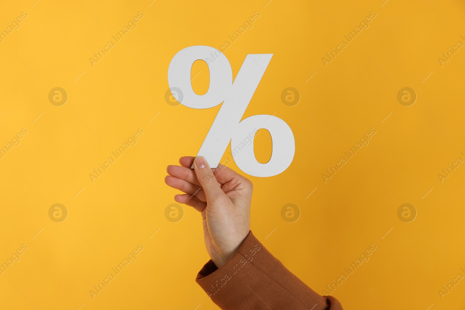 Photo of Woman holding percent sign on orange background, closeup