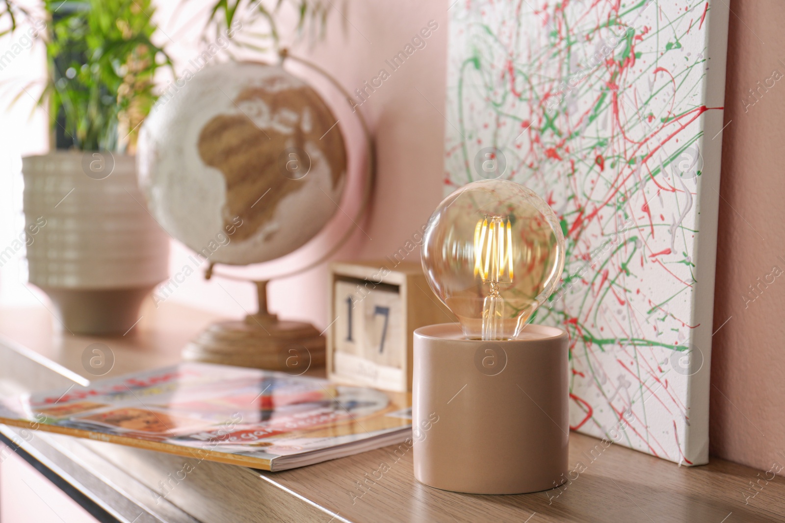 Photo of Modern night lamp and decor on table near pink wall. Space for text