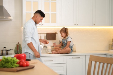 Photo of Little girl with her father cooking together in modern kitchen