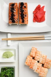 Photo of Delicious sushi rolls served on white wooden table, flat lay