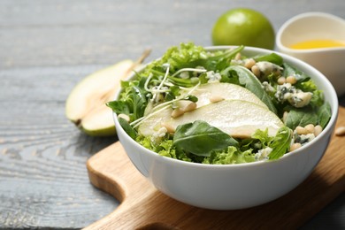 Photo of Fresh salad with pear on grey wooden table, closeup