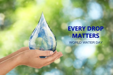 World Water Day. Woman holding icon of drop with Earth image inside on blurred green background, closeup