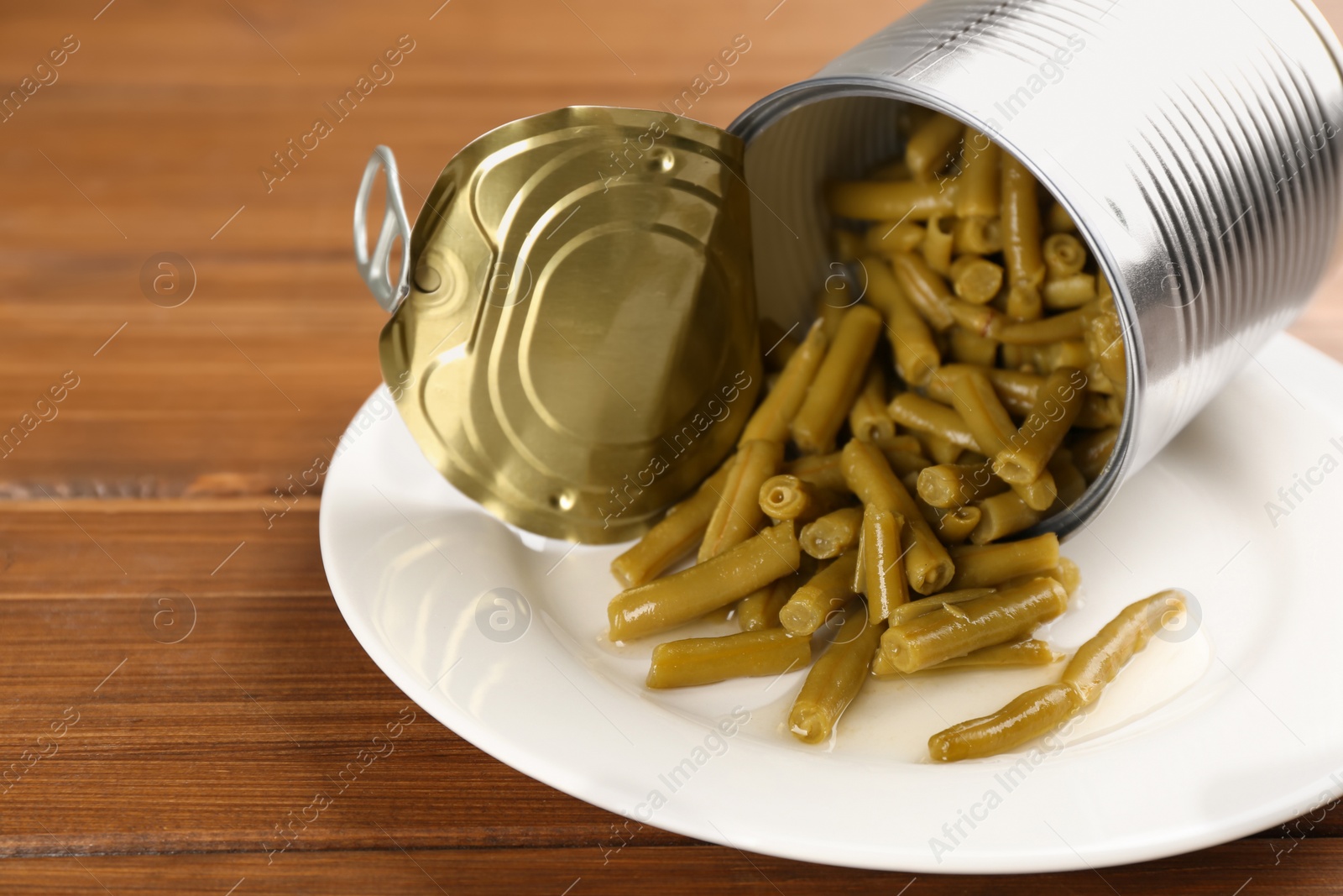 Photo of Canned green beans on wooden table, closeup