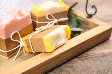 Photo of Natural handmade soap bars in tray on wooden table, closeup