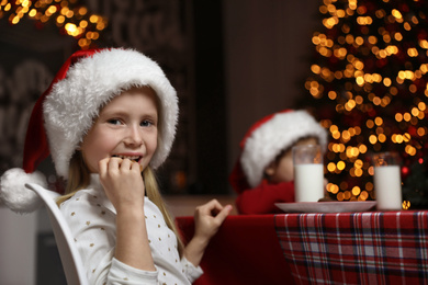 Cute little children eating cookies at table in dining room. Christmas time