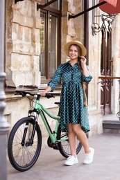 Photo of Young woman with modern bicycle on city street