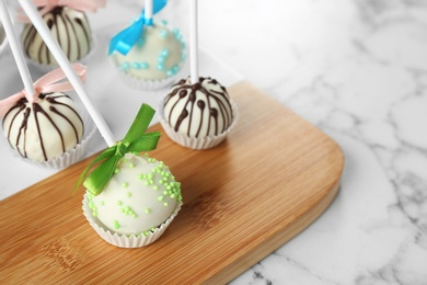 Tasty colorful cake pops on white marble table