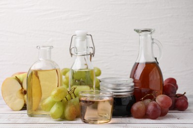 Photo of Different types of vinegar and ingredients on wooden table, closeup