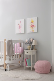 Photo of Children's room with comfortable crib and pictures on grey wall. Interior design
