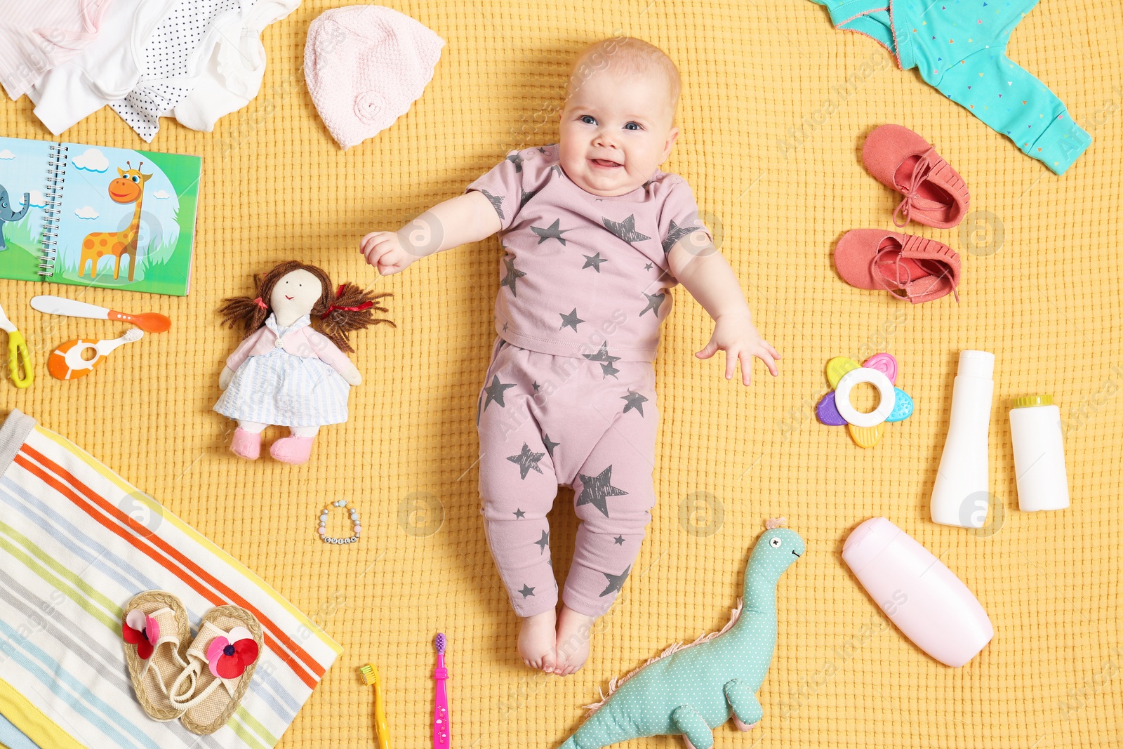 Photo of Cute little baby with clothing and accessories on color blanket, top view