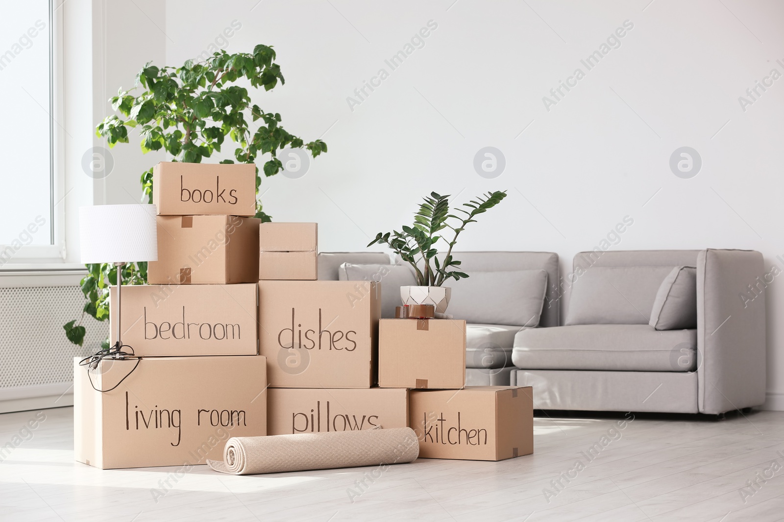 Photo of Pile of moving boxes and household stuff in living room