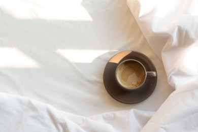 Photo of Aromatic morning coffee on bed, top view. Space for text