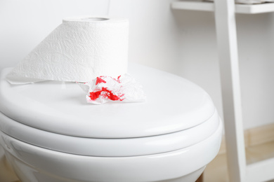 Sheet of paper with blood on toilet bowl in bathroom