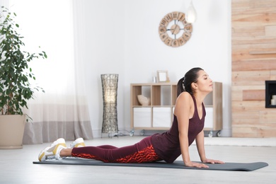 Young woman in fitness clothes doing exercise at home