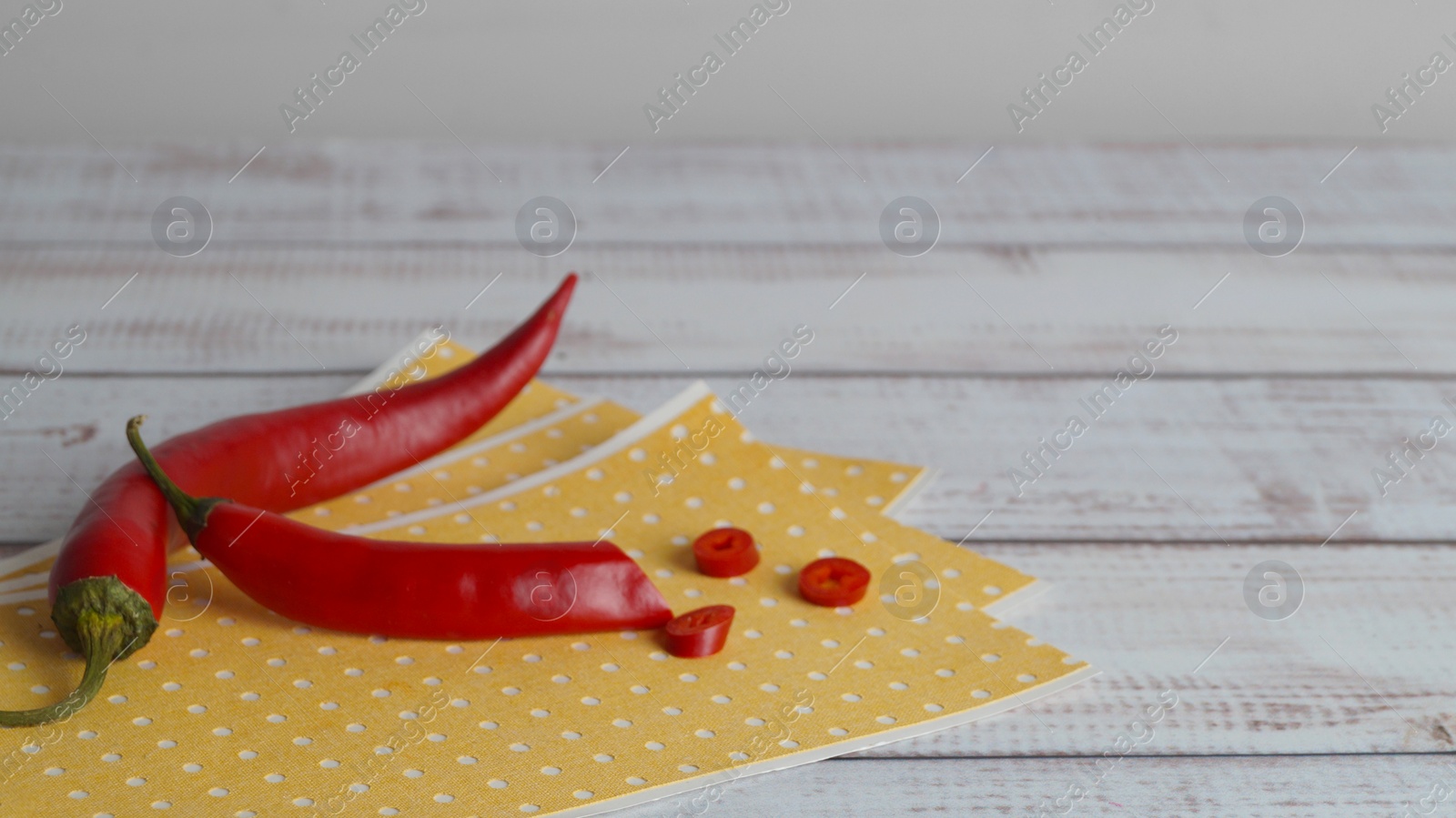 Photo of Many pepper plasters and chili on white wooden table, closeup. Space for text