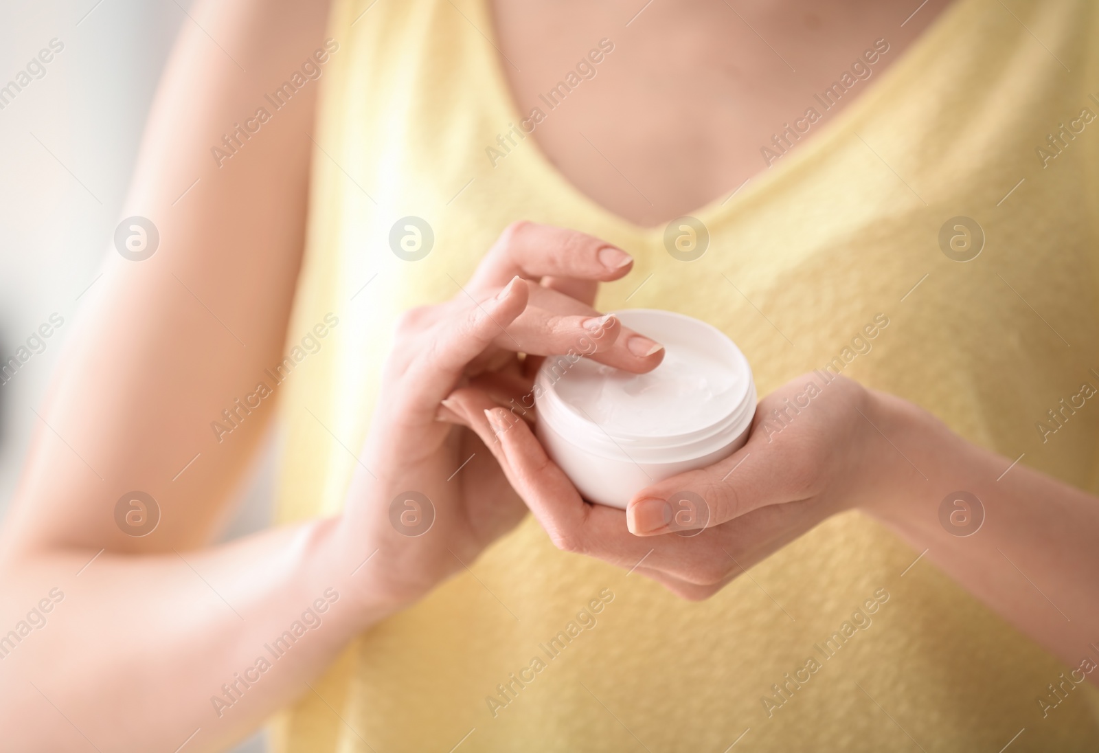 Photo of Young woman holding jar with hand cream, closeup