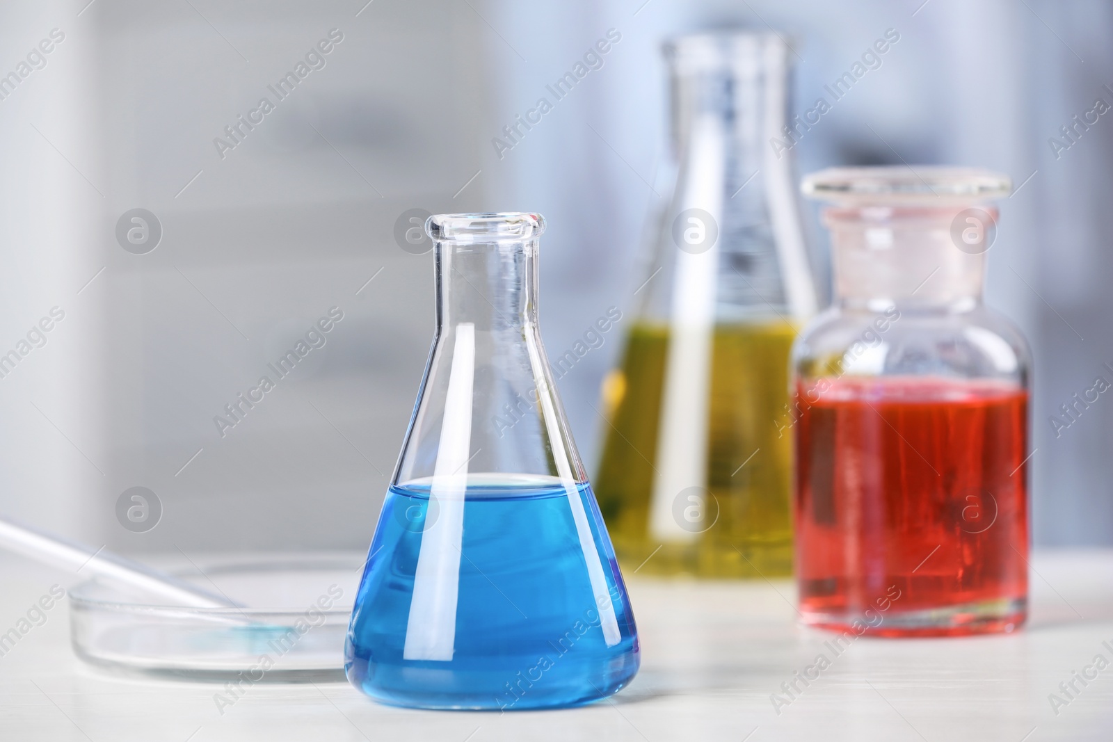 Photo of Laboratory glassware with samples on table indoors. Solution chemistry