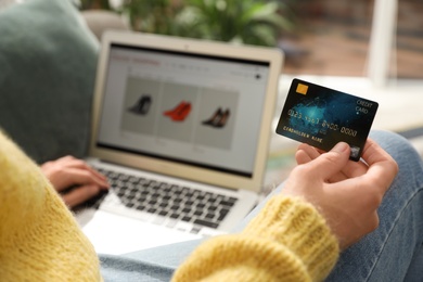 Photo of Woman with credit card using laptop for online shopping indoors, closeup