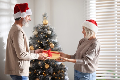Photo of Happy couple holding Christmas gift at home