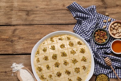 Photo of Making delicious baklava. Raw dough with ingredients on wooden table, flat lay and space for text