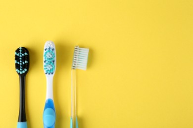 Photo of Different toothbrushes on yellow background, flat lay. Space for text
