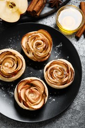 Photo of Freshly baked apple roses on grey table, flat lay. Beautiful dessert