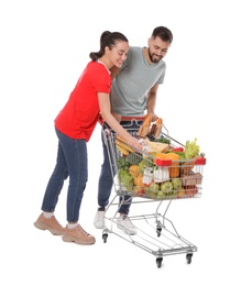 Photo of Happy couple with shopping cart full of groceries on white background