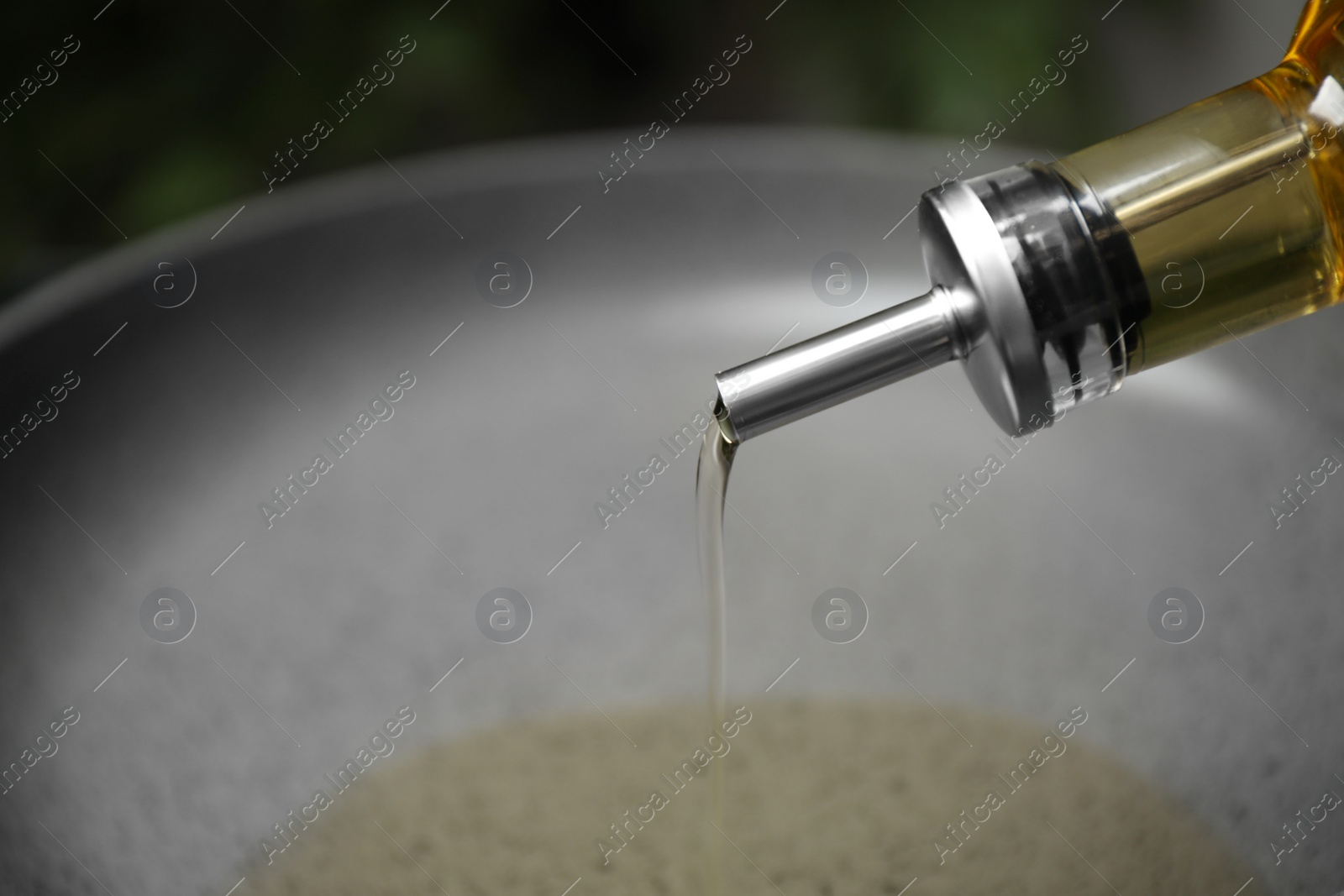 Photo of Pouring cooking oil from bottle into frying pan, closeup