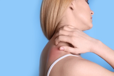 Woman with allergy symptoms scratching neck on color background, closeup. Space for text