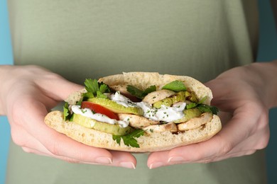 Photo of Woman holding delicious pita sandwich with grilled vegetables and sour cream sauce, closeup