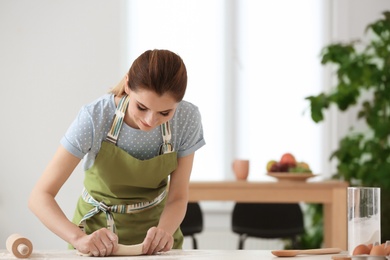 Photo of Woman preparing dough on table in kitchen