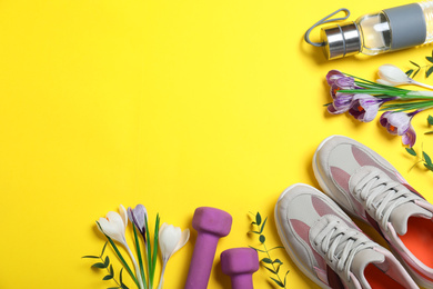 Photo of Flat lay composition with spring flowers and sports items on yellow background. Space for text