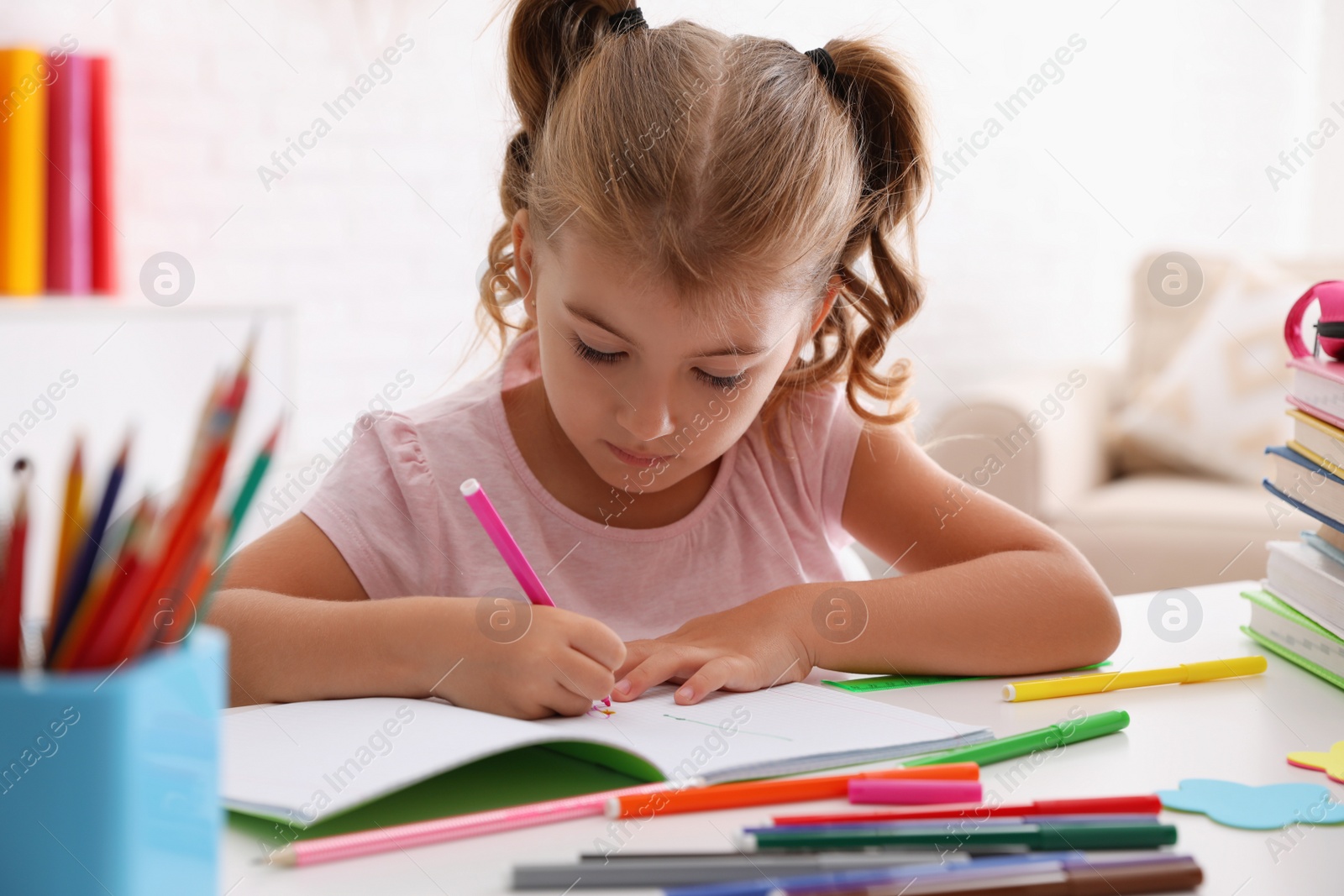 Photo of Cute little girl doing homework at table