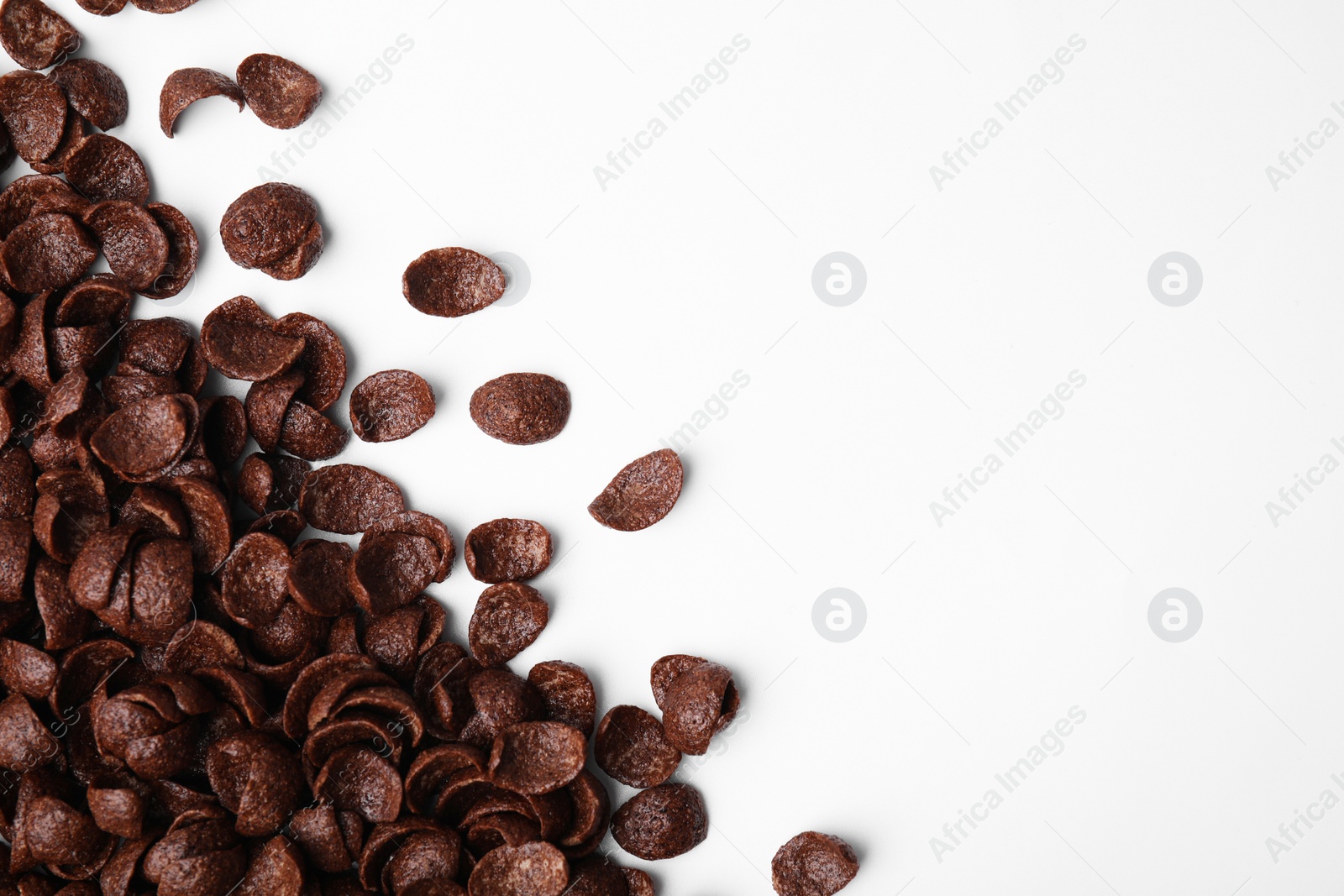 Photo of Breakfast cereal. Chocolate corn flakes on white background, flat lay. Space for text