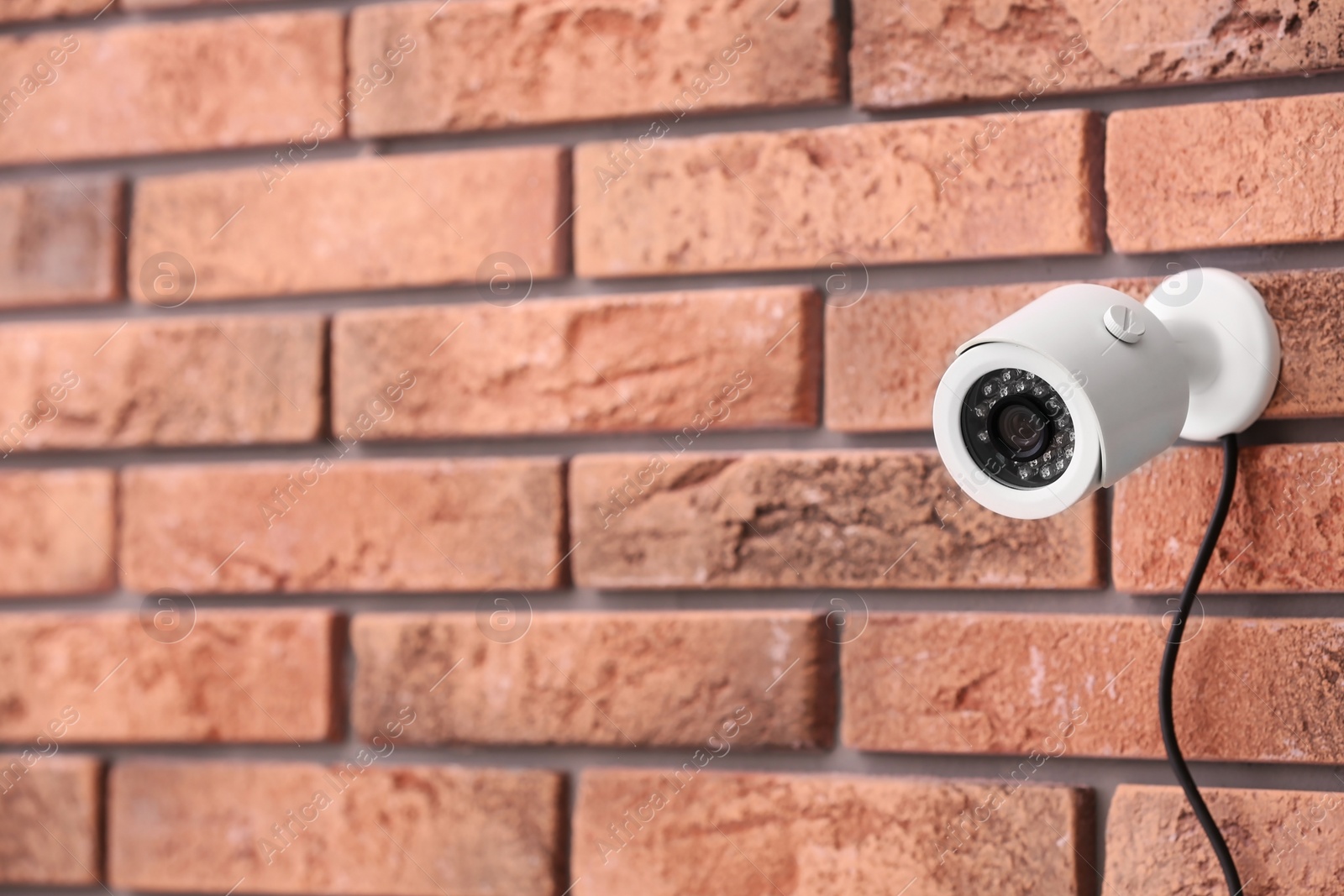 Photo of Modern security CCTV camera on brick wall