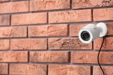 Photo of Modern security CCTV camera on brick wall