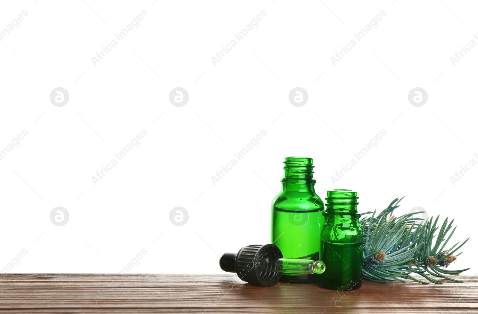 Photo of Bottles of essential oil, pipette and pine branch on table against white background